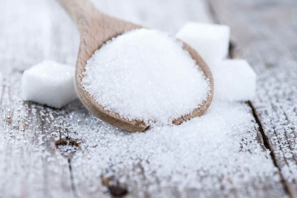 A spoonful of Sugar and sugar cubes on a wooden table. Aspartame vs sucralose